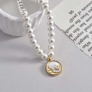 Elegant pearl necklace with a gold star and moon face pendant on a white shell base