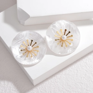 Détail macro de boucles d'oreilles perles avec fleurs dorées sur présentoir en pierre