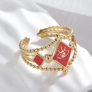 Detailed close-up of golden evil eye ring with red enamel and diamond-like rhinestone