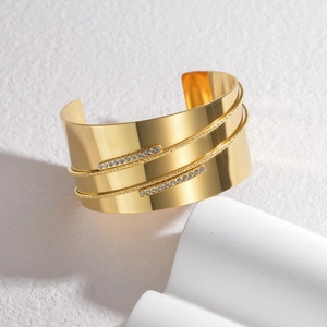 Detailed view of an 18K gold-plated double-row crystal cuff bangle on a stone pedestal