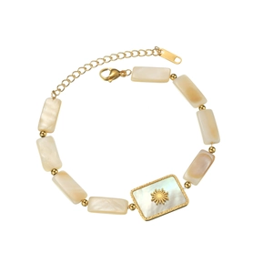 Bracelet en acier doré avec perles en nacre et pendentif soleil sur fond blanc pur