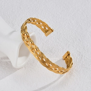 Bohemian gold woven wire cuff bracelet with metal bead accents on white ceramic stand