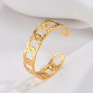 Macro detail of gold-plated chunky chain cuff bracelet with textured hammered finish