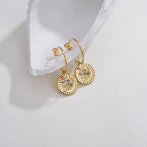 Macro view of gold hoop earrings with star and moon charms featuring multicolor stones