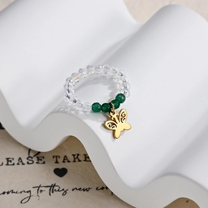 Detail showing transparent faceted beads and golden butterfly pendant on an elastic ring