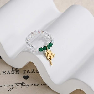 Macro shot of elastic beaded ring with green jade beads and golden rose pendant