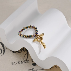Macro shot of colorful iridescent beaded ring with a gold heart-winged key pendant