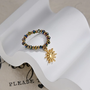 Detail of beaded ring with gold beads, iridescent crystals and a sun charm on stand