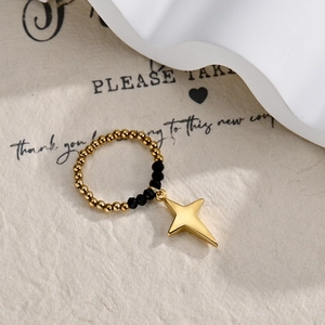 Detail of beaded stretch ring with black faceted beads and gold star charm pendant