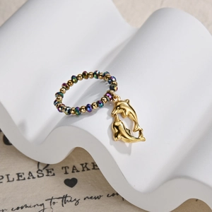 Macro view of gold beaded ring with colorful facets and twin dolphin charms