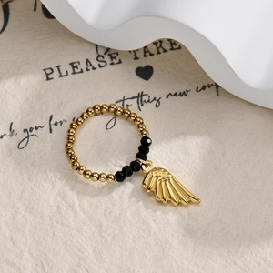 Detailed close-up of golden beaded ring with a delicate hanging feather pendant charm