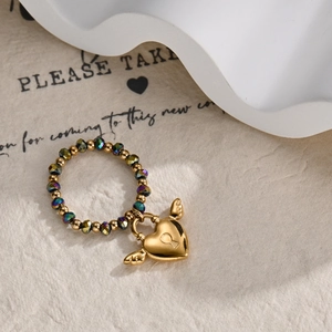 Detail of beaded ring with gold heart lock charm and small wing accents on band