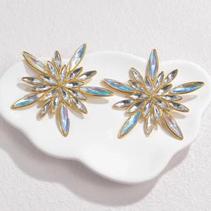 Chic gold flower stud earrings with colorful zircon crystals on a white ceramic tray