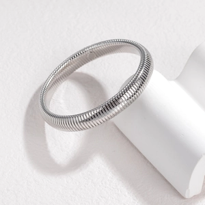 Silver stainless steel spiral bangle with high-polished metallic texture on white stone