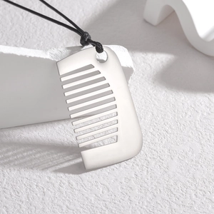 Minimalist silver comb pendant on black cord necklace displayed on white stone