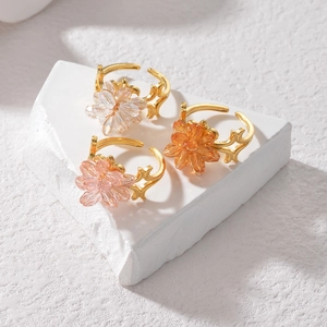Close-up of gold-plated flower rings with crystal petals and hollow engraved bands