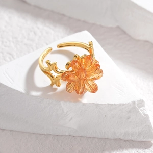 Adjustable gold vintage ring with orange crystal flower on textured stone background