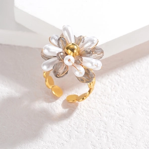 Fashionable floral bead ring with gold metal base and faceted grey crystal on white platform