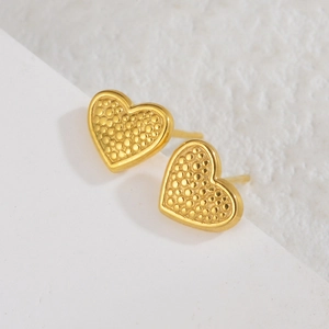 Elegante goldene Herzohrstecker mit Reliefstruktur auf steinernem Hintergrund