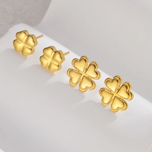 Golden stainless steel four-leaf clover stud earrings set on a white elegant display