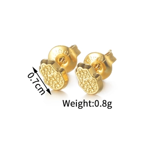 Macro detail of gold Hamsa hand earrings in stainless steel with textured finish