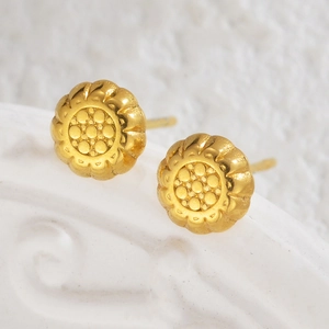 Macro detail of 18K gold-plated floral stud earrings with textured petals and center