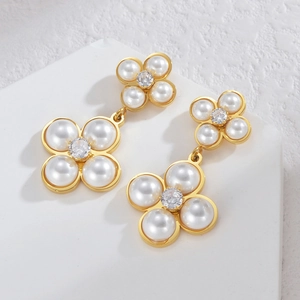 Elegant gold double clover pearl earrings with zircon center on a stone display