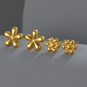 Elegant 18K gold plated sunflower and clover stud earrings set on a minimalist pedestal