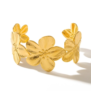 Golden wide cuff bracelet with textured floral design and minimalist open structure
