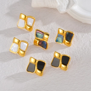 Detail of square vintage earrings with shell and enamel inlays on a stone surface