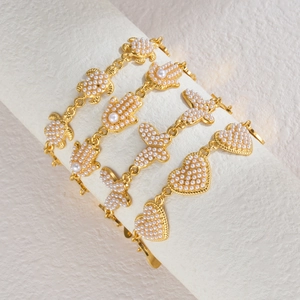 Détail de bracelets plaqués or 18 carats avec breloques papillon et cœur en perles