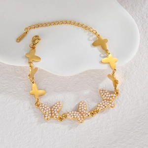 Bracelet papillon en acier inoxydable doré avec perles sur un support blanc