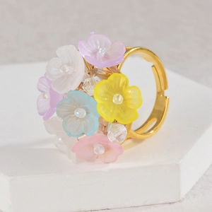 Adjustable gold ring with colorful resin flowers and crystals on a white stone base