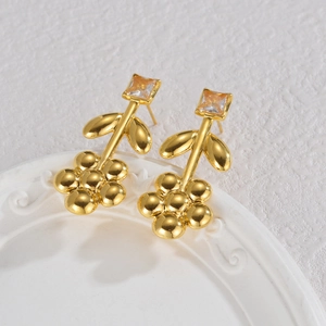 Boucles d'oreilles fleur plaqué or 18K avec pierre carrée sur assiette blanche