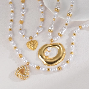 Multi-layer pearl necklace with heart pendant and gold metal accents on a white plate