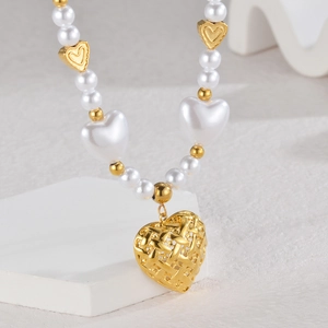 Detail of woven gold heart pendant on white pearl necklace with metallic accents