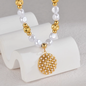 Detail of vintage pearl pendant necklace with gold beads on a white display stand