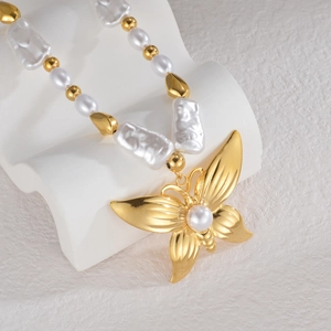 Macro shot of 18K gold butterfly pendant featuring a white pearl on a baroque pearl chain