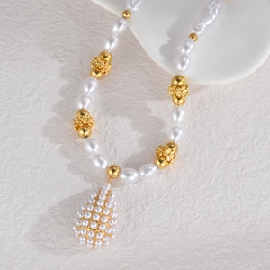 Close-up of pearl necklace with gold floral spacers and teardrop shaped pearl pendant