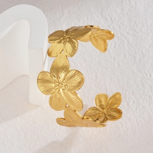 Gold hollow floral open bangle featuring five detailed petals on white geometric stand