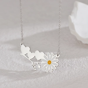 Détail d'un collier pendentif cœur et marguerite sur un socle blanc texturé élégant