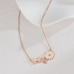 Gros plan d'un collier or rose avec pendentif marguerite et trois cœurs en détail