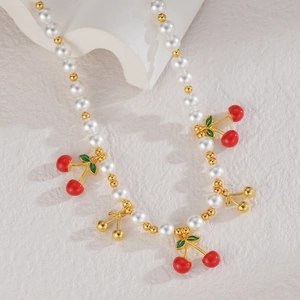 Détail du collier cerise avec perles blanches et pendentifs en émail rouge
