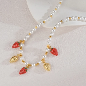Gros plan de pendentifs fraises et de perles sur un collier style printanier doux