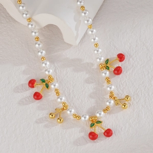 Collier de perles exquis avec pendentifs cerises rouges et dorés sur fond minimaliste