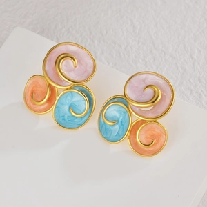 Detailed macro view of spiral geometric earrings with gold finish and tricolor enamel inserts