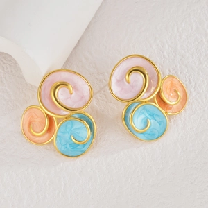 Macro shot of colorful spiral enamel stud earrings with golden edges on marble