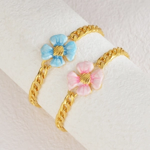 Bracelets gourmettes dorés avec breloques fleurs bleues et roses sur support blanc