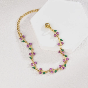 Detail of gold cherry bracelet with purple glitter fruit and green enamel leaves