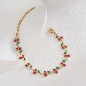Close-up of a gold cherry bracelet with red glitter charms and adjustable chain